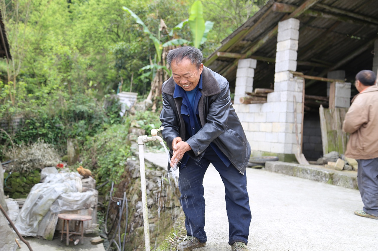 大营镇大营村鼠场坡组村民韦堂国打开房前水龙头洗手.JPG