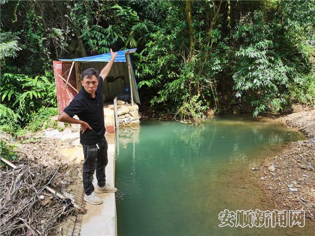 韦朝忠向记者介绍蔬菜基地的水源点.jpg